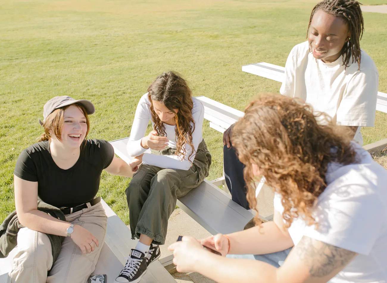 Friends outside on bleachers, laughing.