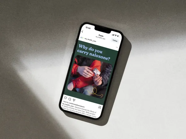 Image of a phone with a person handing an individual naloxone