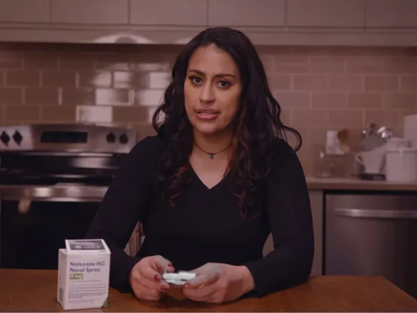 A person holding a naloxone nasal spray, demonstrating how to use it.