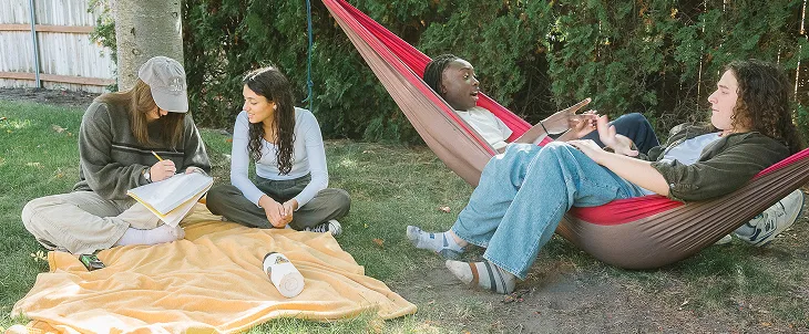 Friends hang outside on blanket.